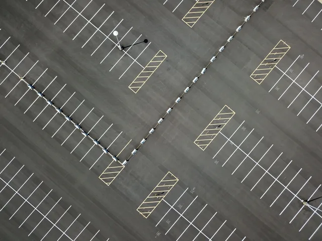 Top-down view of a large, empty parking lot featuring clear lines and patterns. Parking lot striping expansion: four growth moves, what each breaks, and how to sequence them