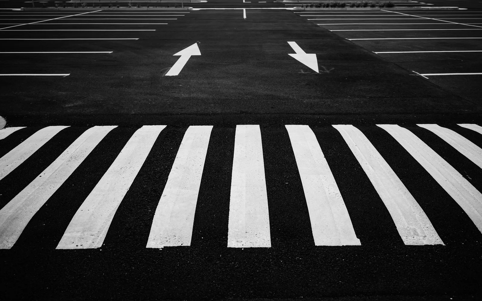 Black and white image of a parking lot with zebra crossing and directional arrows. Parking lot striping startup: buyers, season, first steps