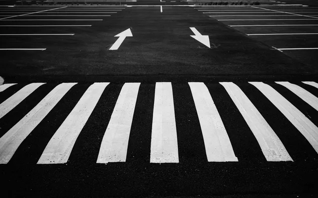 Black and white image of a parking lot with zebra crossing and directional arrows. Parking lot striping startup: buyers, season, first steps