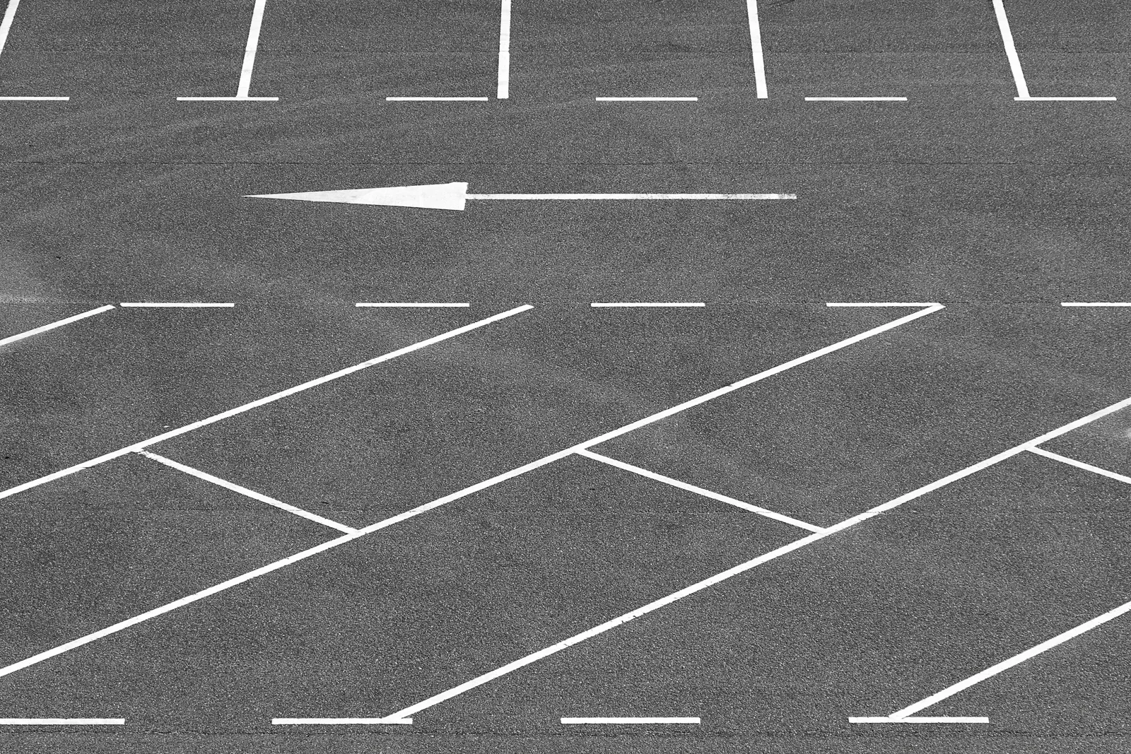 A minimalist view of an empty parking lot with directional arrow and parking lines. How long does parking lot striping take per parking stall?