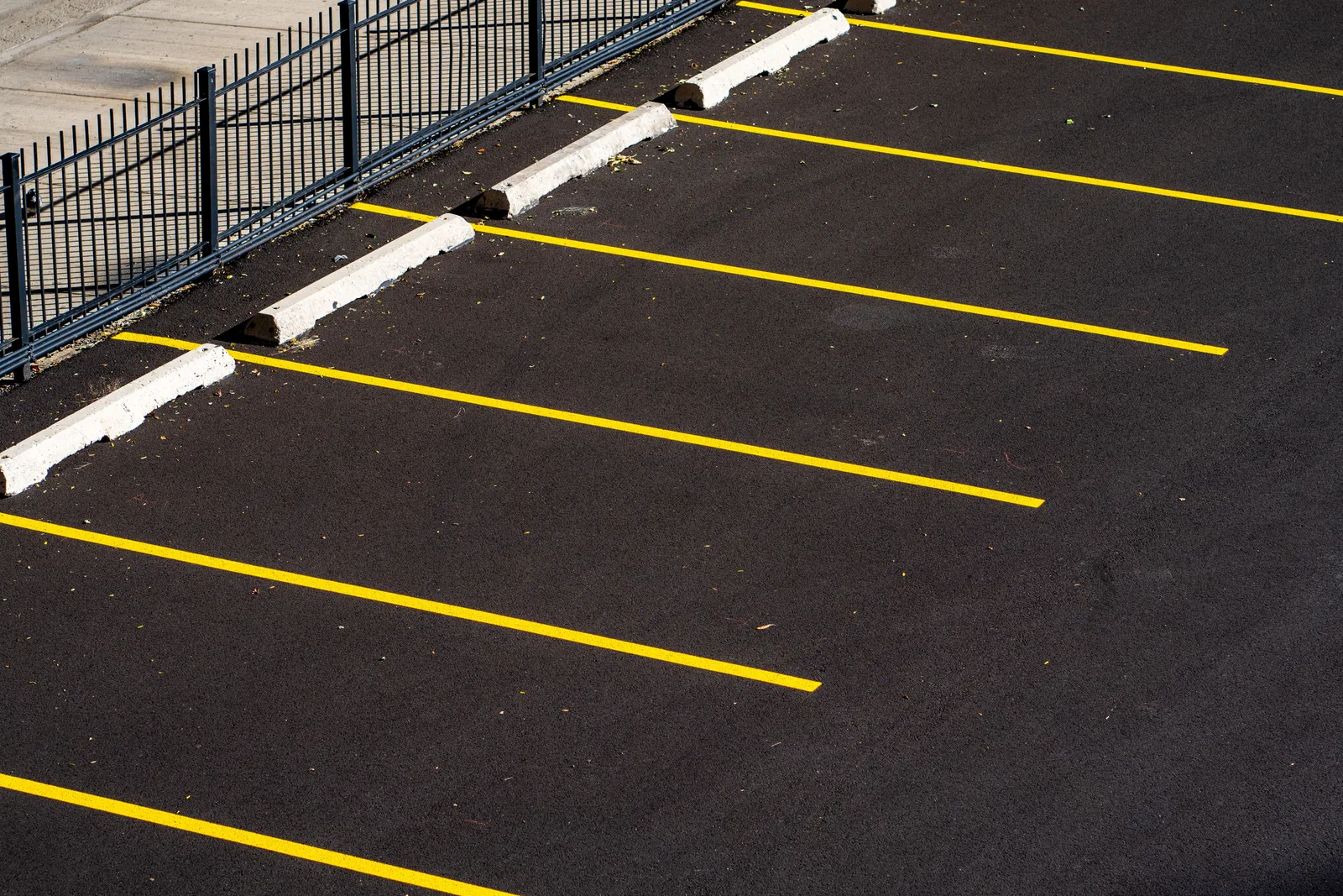 Top view of an empty parking lot with yellow lines and a metal fence, perfect for urban scenes. How SBA loans and APWA design standards fit a US striping business