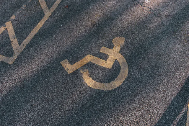 Close-up of an asphalt parking spot with a yellow wheelchair symbol for accessibility. How Texas and Florida property managers buy striping work